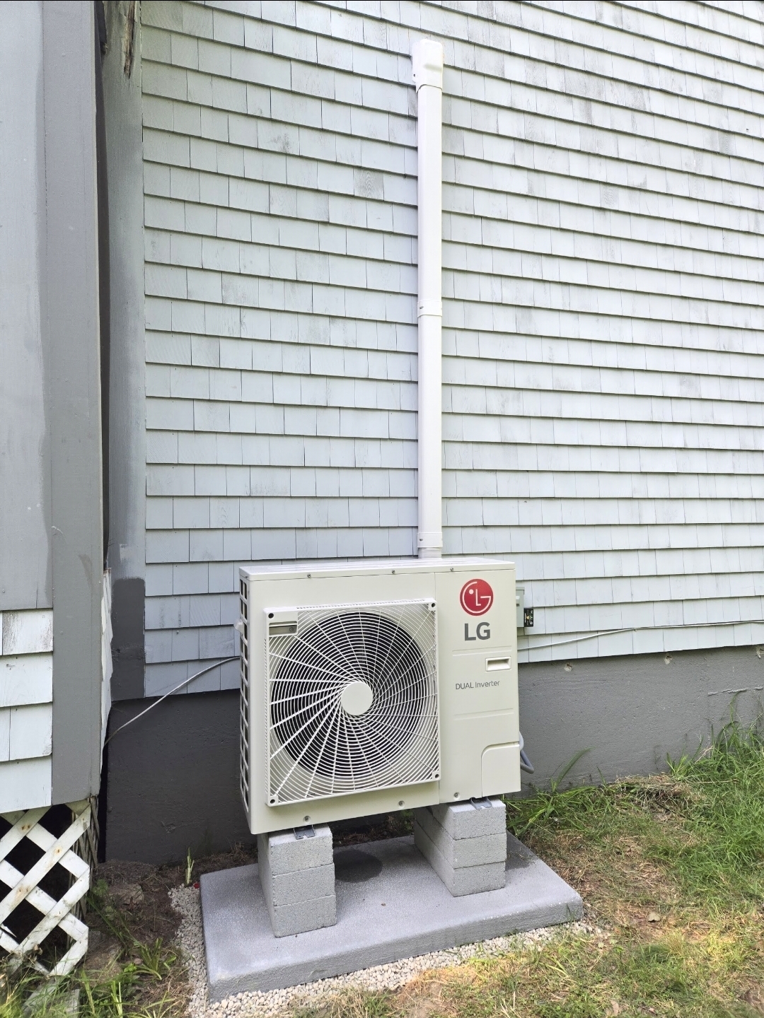 LG Dual Inverter outdoor unit on a concrete pad with a concealed line-set run